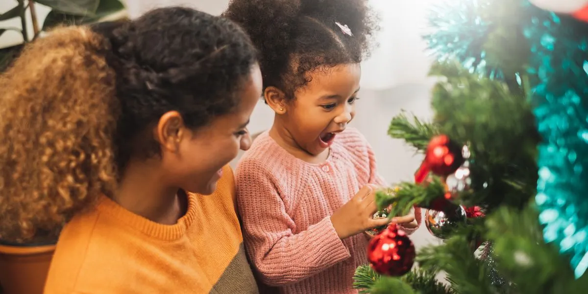 Holiday health and safety tips - Mother and daughter putting ornaments on christmas tree