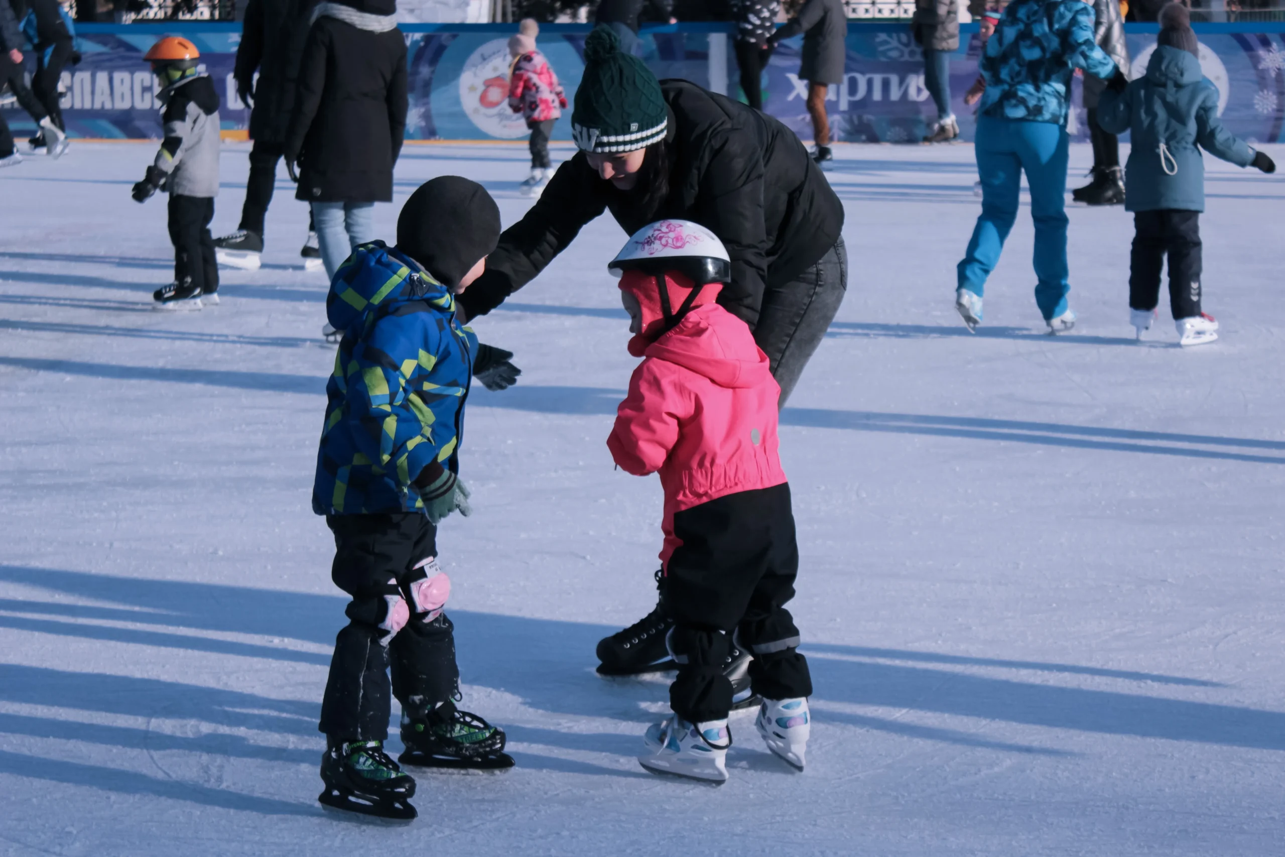 Woman with her kids showing them how to ice skate