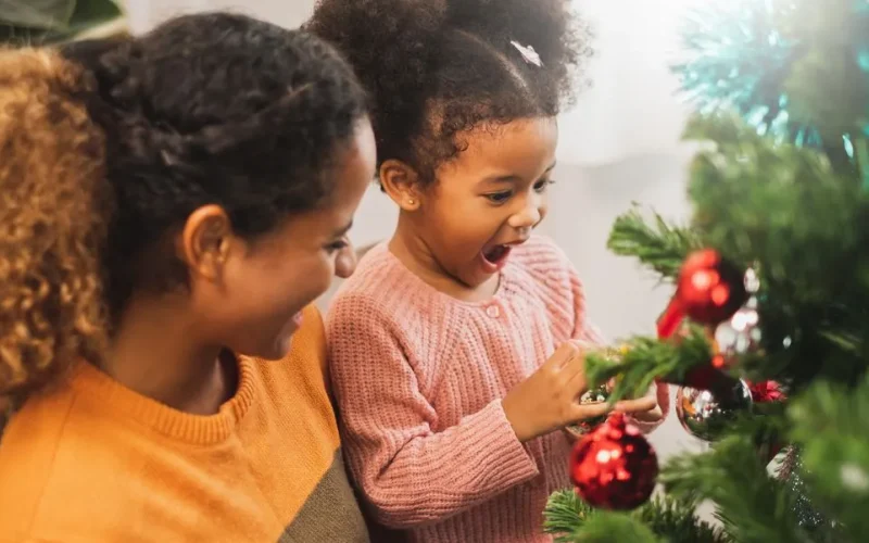 Holiday health and safety tips - Mother and daughter putting ornaments on christmas tree